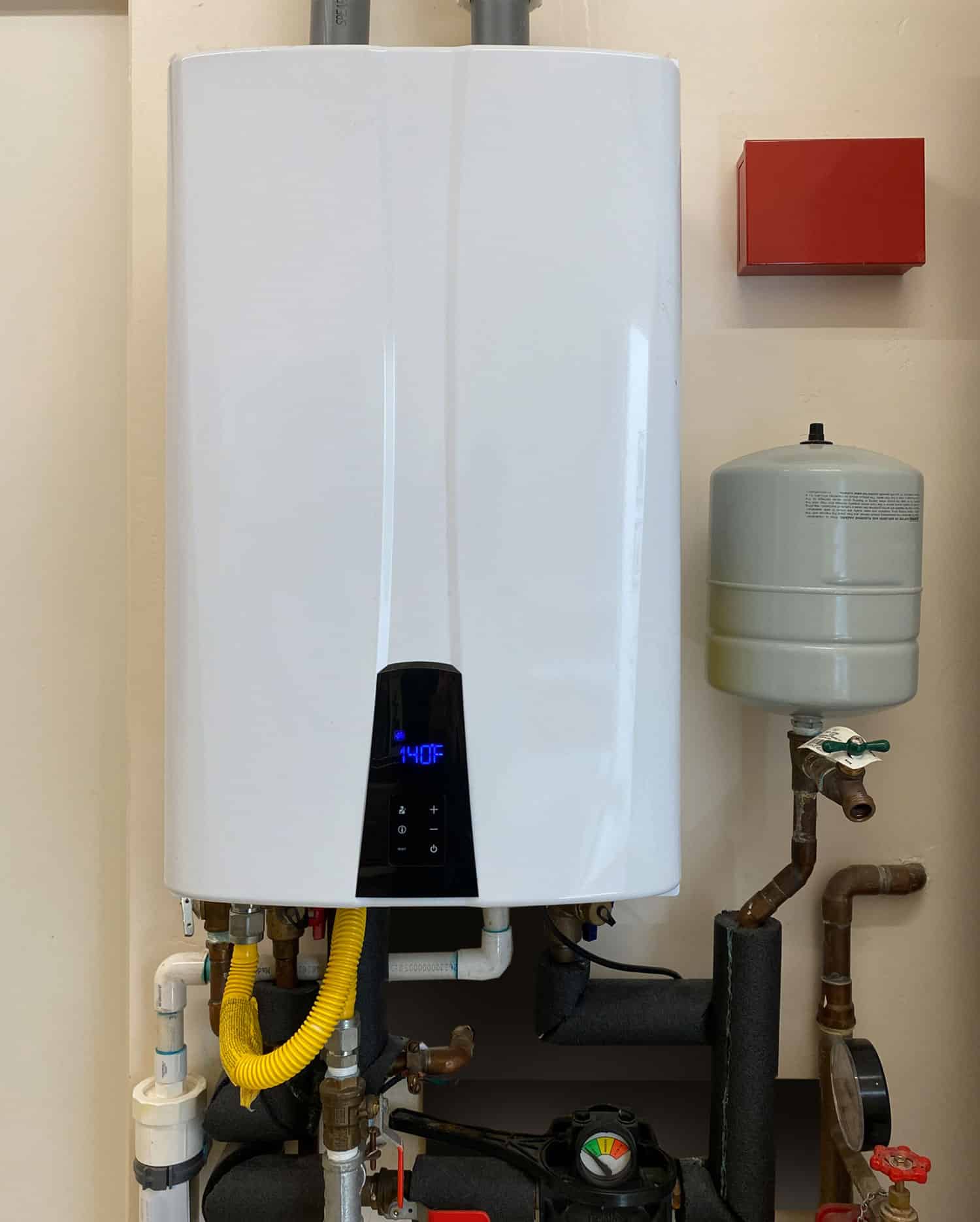 Professional tankless water heater installation with digital temperature display in a residential utility room.